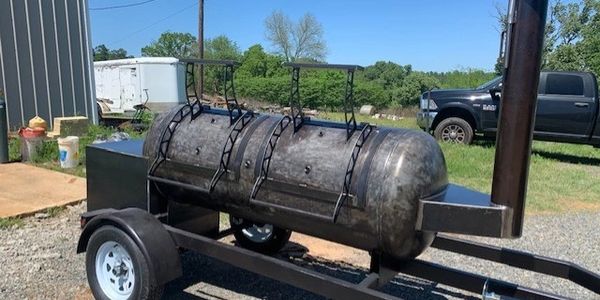 Large smoker grill on a trailer outdoors.