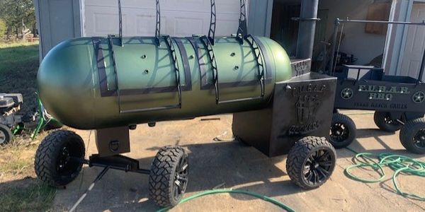 Outdoor barrel grill with wheels and hooks, camo green.