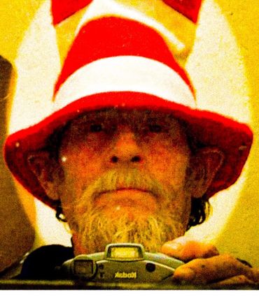 Man with a beard wearing a red and white striped hat, holding a Kodak camera.