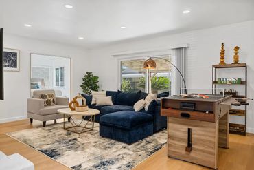Modern living room with navy sectional, foosball table, and large window.