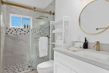 Modern bathroom with glass shower, hexagonal tile accents, and white vanity.