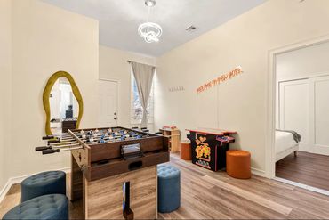 Game room with foosball table and arcade machine, cozy seating, and bright decor.