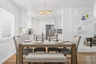 Modern dining room with beige chairs, a bench, and a golden chandelier.
