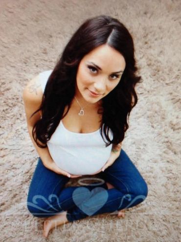 Pregnant woman sitting cross-legged, smiling.