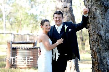 Happy couple in wedding attire posing outdoors.