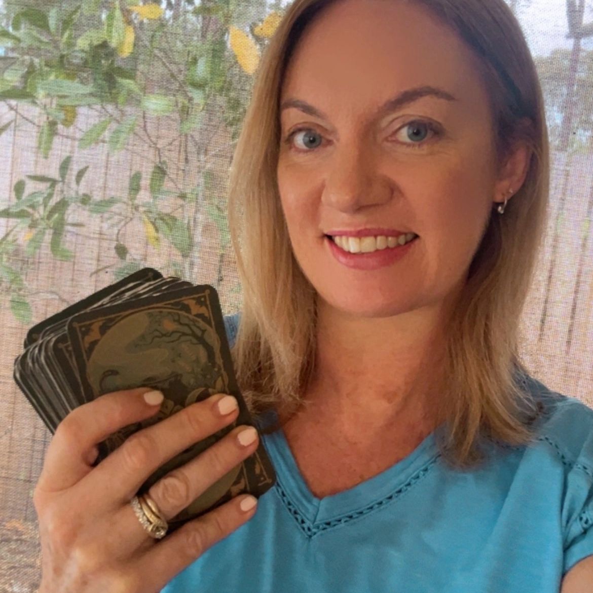 Woman holding a deck of cards and smiling.