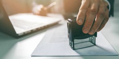 Persona sellando documentos. Haciendo referencia a la certeza de los trámites realizados