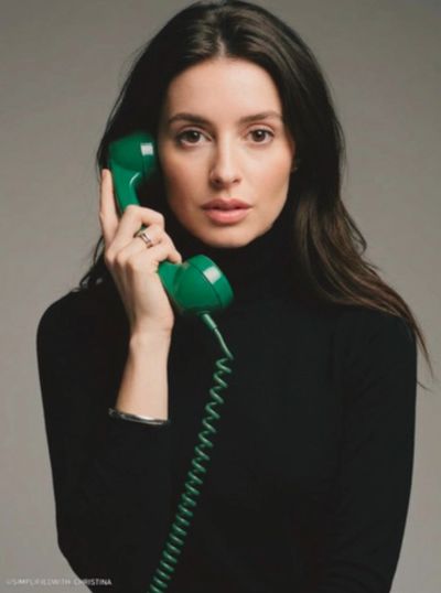 Woman in black turtleneck holding a green vintage telephone receiver.
