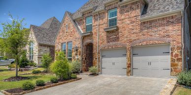 Brick house with a two-car garage and landscaped yard.