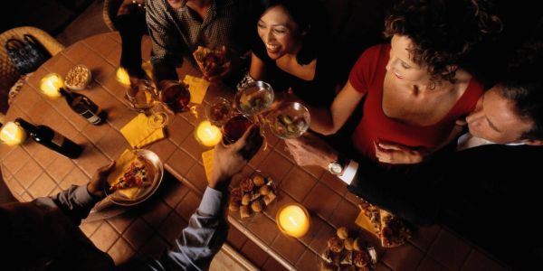 Friends toasting with drinks around a cozy table.