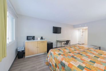 Cozy motel room with two beds, a TV, and a small kitchenette area.