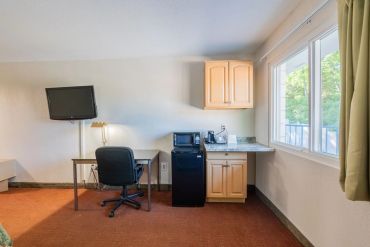 Small kitchenette and workspace with TV in a room with large window.