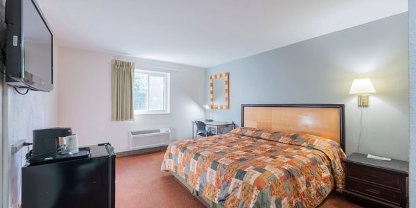 Cozy motel room with king-sized bed and TV.