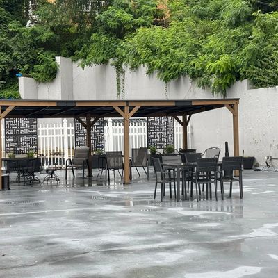 Outdoor seating area with tables and chairs under a wooden pergola.
