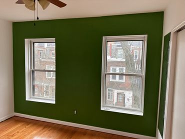 Room with two windows and a green accent wall.