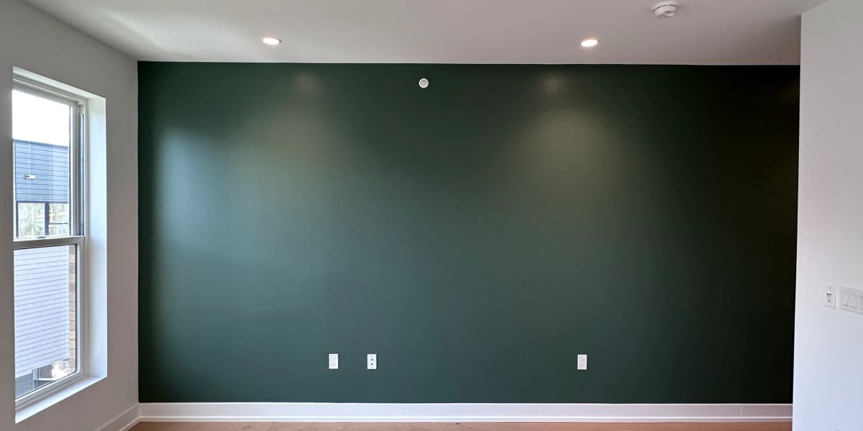 Empty room with a dark green accent wall and window.