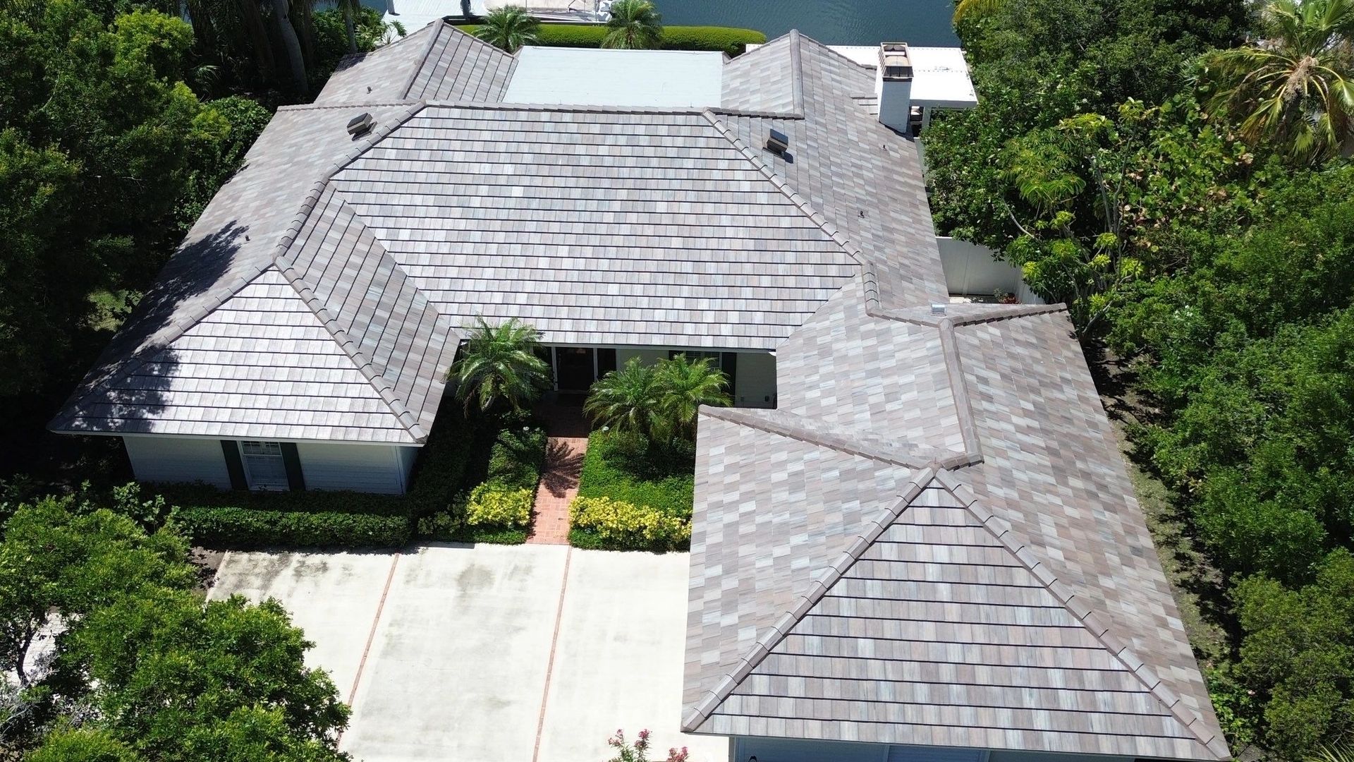 A large house with a gray tiled roof surrounded by greenery.
