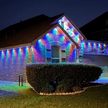 House exterior illuminated with colorful LED lights at night.