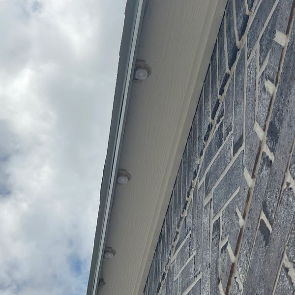 Close-up of a brick wall with overhead lights under an overcast sky.