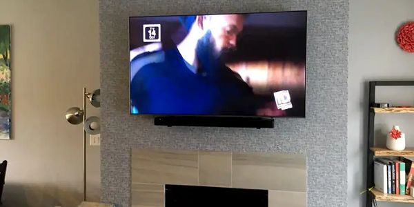 Flat screen tv hung on wall over marble fireplace in the rogue valley with samsung surround sound.