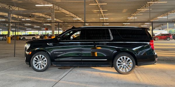 Black luxury SUV parked in a covered lot with reflective windows.