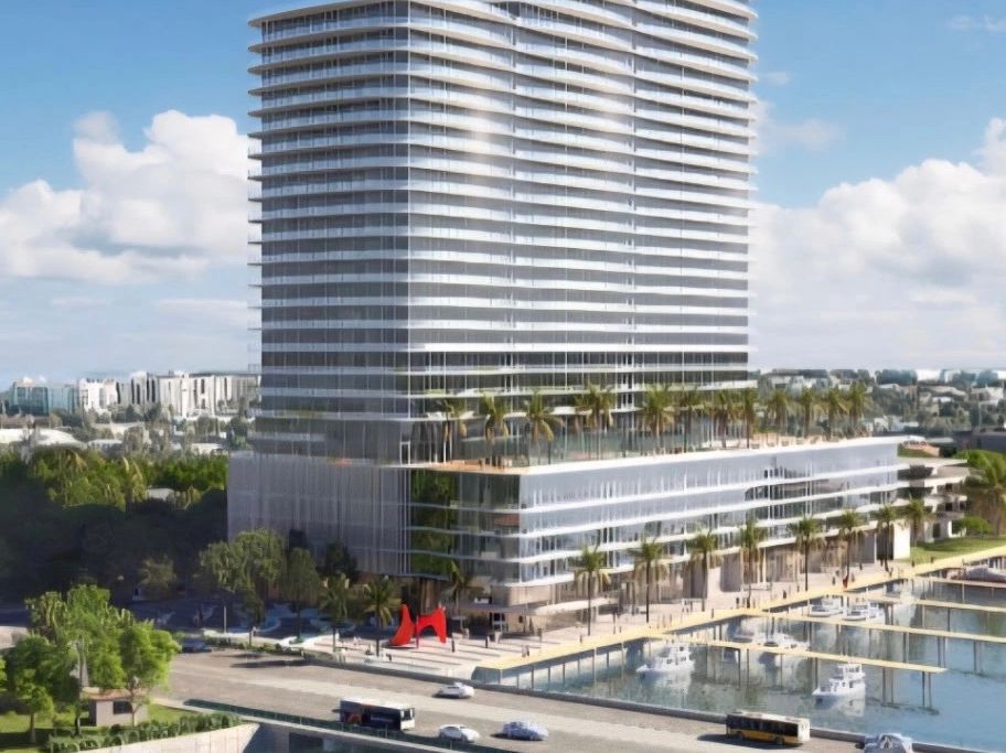 Modern high-rise building with waterfront view and palm trees.