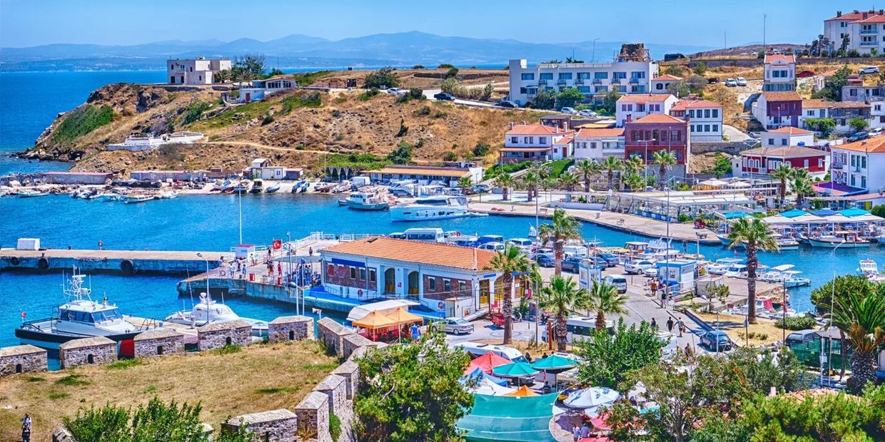 Colorful coastal town with boats docked and people enjoying a sunny day near the water.