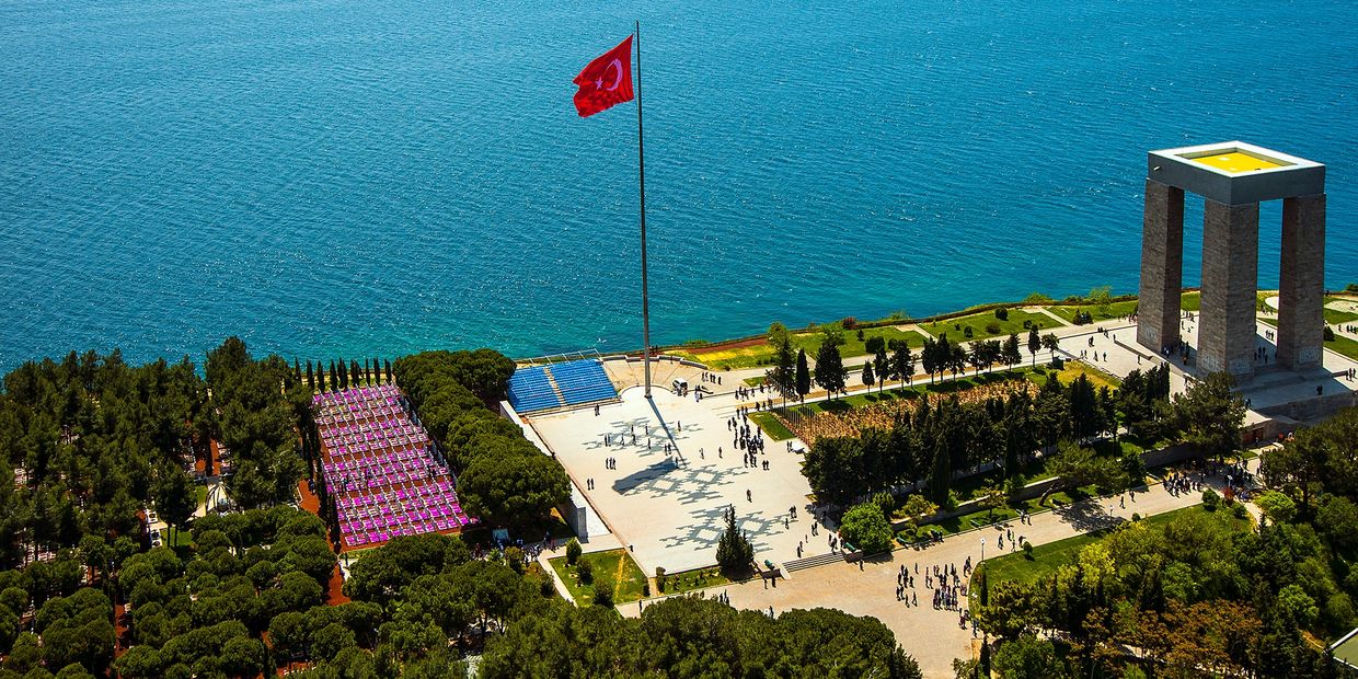 Aerial view of a Turkish memorial with a large flag and monument by the sea.