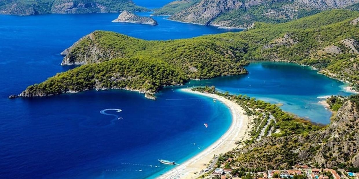 A stunning aerial view of a crescent-shaped beach with turquoise waters and lush green hills.