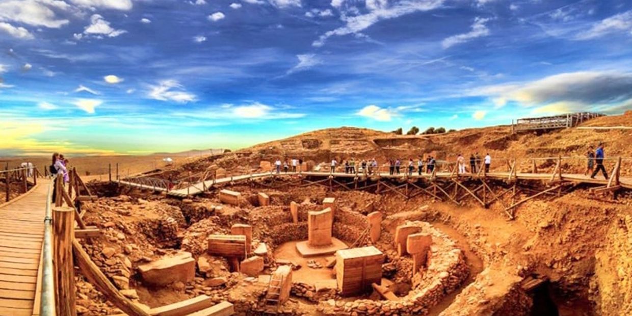 Ancient archaeological site with stone structures under a bright blue sky.
