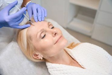 Woman receiving a cosmetic injection in her forehead at a clinic.