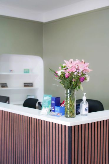 Reception desk with flowers and hand sanitizer.