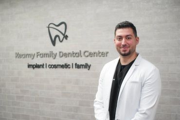 Dentist standing by dental center sign.