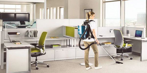 office cleaning lady using a vacuum to clean an office space