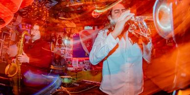 Josue Estrada playing trumpet with the band in a psychedelic whirl.