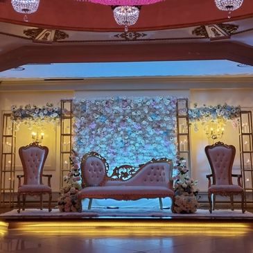 Elegant wedding stage with floral backdrop and vintage seating.