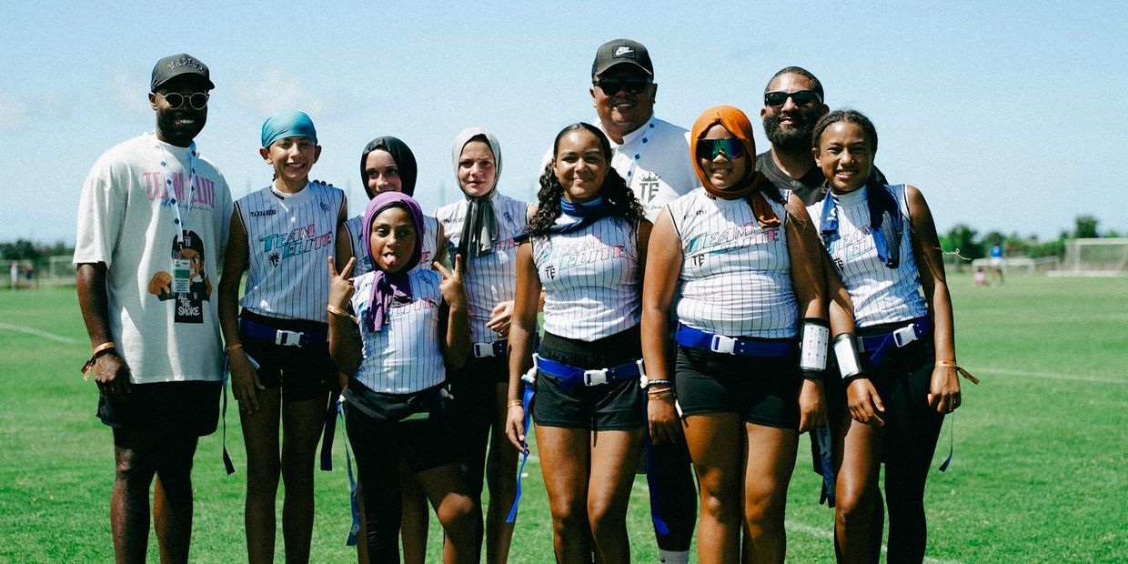 Youth flag football team posing together on a sunny day.