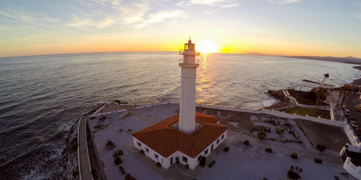 Sunset behind a coastal lighthouse.