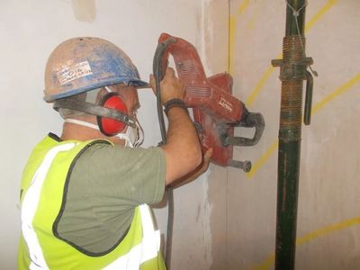 A man, cutting trough a wall.