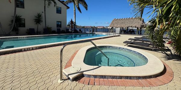 Outdoor pool and jacuzzi under clear blue sky.