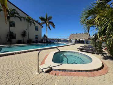 Outdoor pool and jacuzzi under clear blue sky.