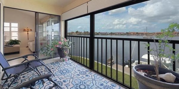 Balcony with chairs overlooking water and boats.
