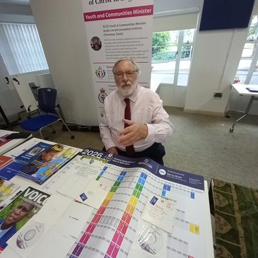 Man presenting at a youth and communities event table.