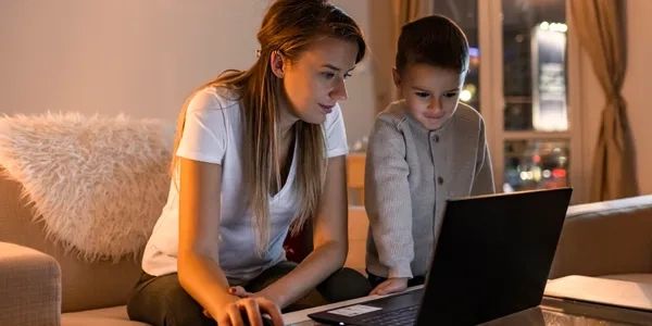 Woman and child using a laptop together in a cozy living room.