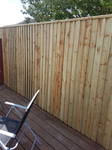 New wooden fence with outdoor chairs on a deck.