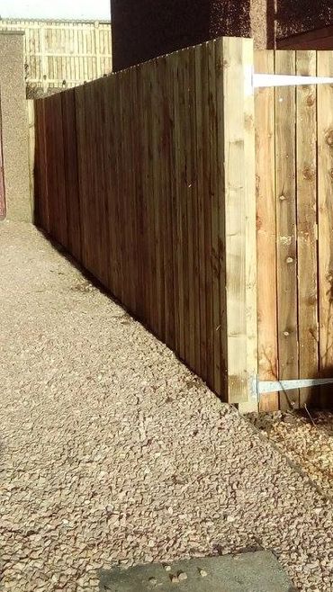 Wooden fence and gate along a gravel pathway beside a building.