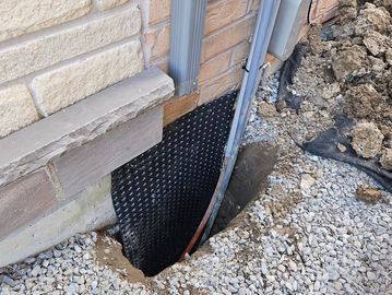 A foundation wall with waterproofing membrane exposed.