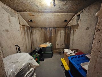 Cluttered basement storage room with concrete walls.