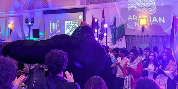A person in a gorilla costume entertains a crowd at an Arabian Night event.