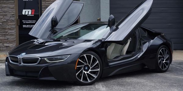 Black BMW i8 with butterfly doors open.